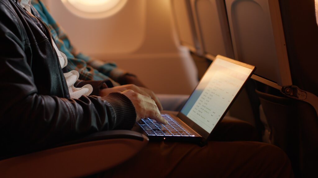 Tired employee travelling by airplane and working on laptop