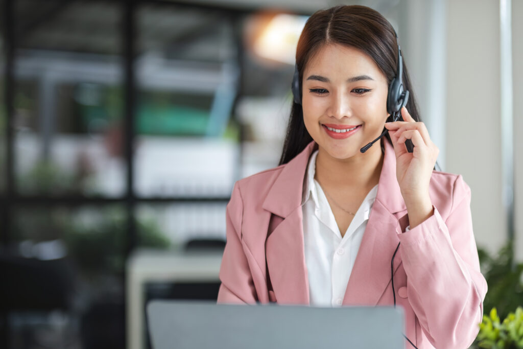 A call center operator is explaining job details to a customer on a laptop.